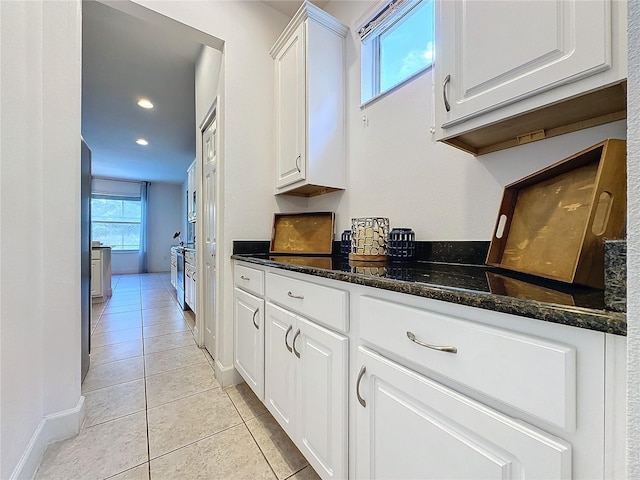 kitchen featuring dark stone countertops, white cabinets, and light tile patterned floors