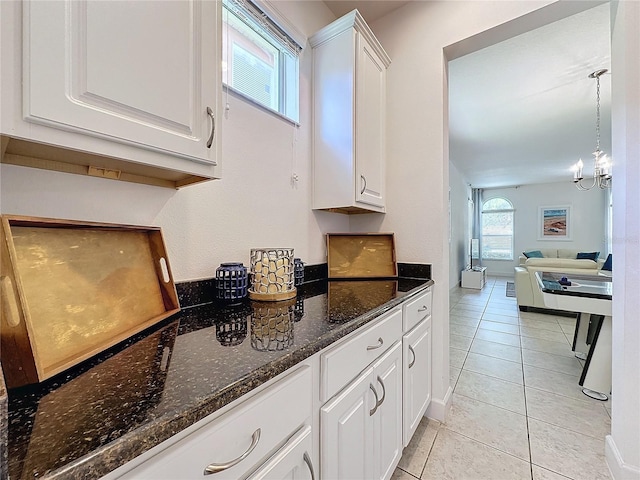 kitchen featuring dark stone countertops, white cabinetry, light tile patterned floors, and decorative light fixtures