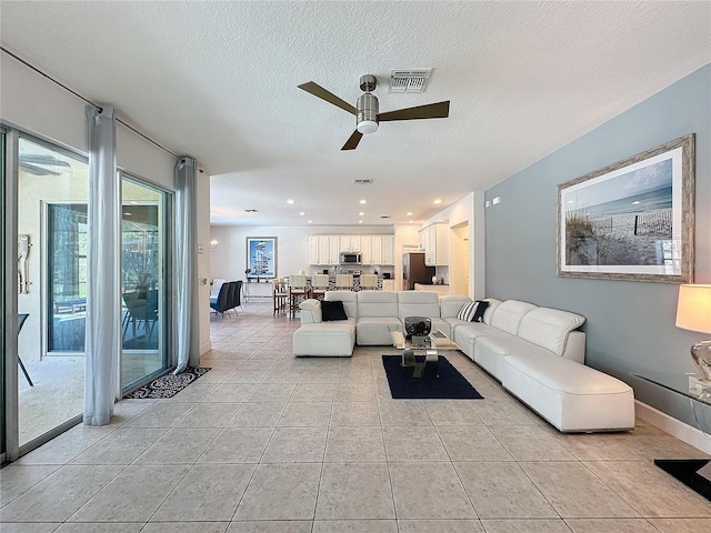 tiled living room with a textured ceiling and ceiling fan