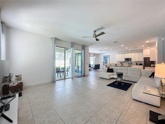 tiled living room with ceiling fan and a textured ceiling