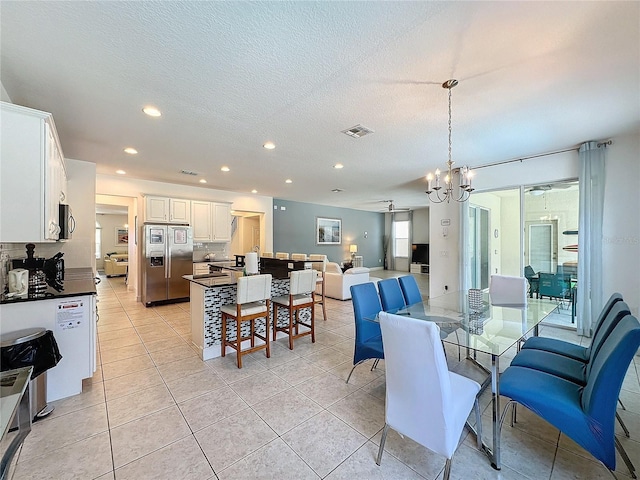 tiled dining room with an inviting chandelier and a textured ceiling