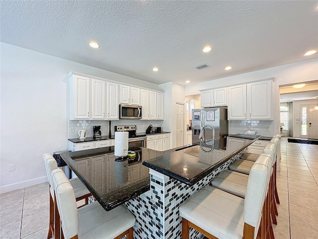 kitchen with a kitchen breakfast bar, white cabinets, stainless steel appliances, and a large island