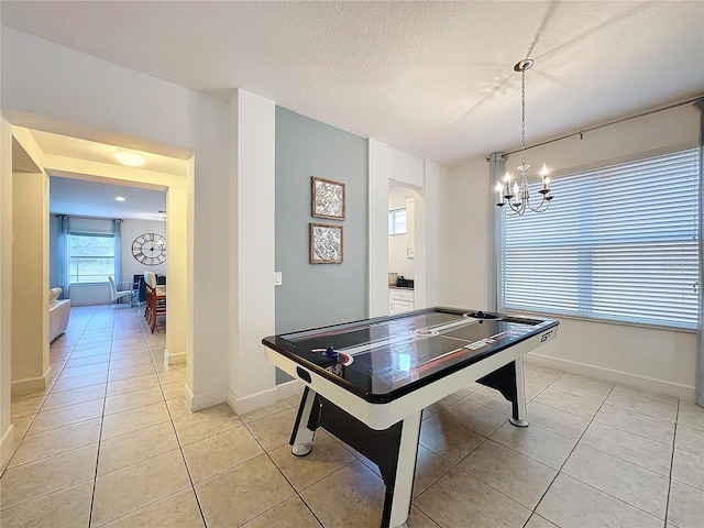 game room featuring a notable chandelier, light tile patterned floors, and a textured ceiling