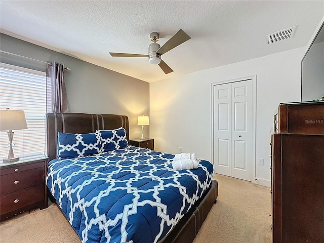 bedroom featuring a textured ceiling, light carpet, and ceiling fan