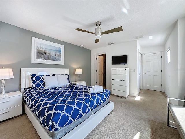 bedroom with a textured ceiling, ceiling fan, and light colored carpet