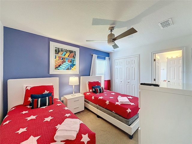 carpeted bedroom with a textured ceiling, a closet, and ceiling fan