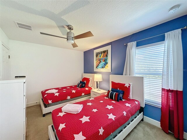 bedroom featuring a textured ceiling, light colored carpet, and ceiling fan