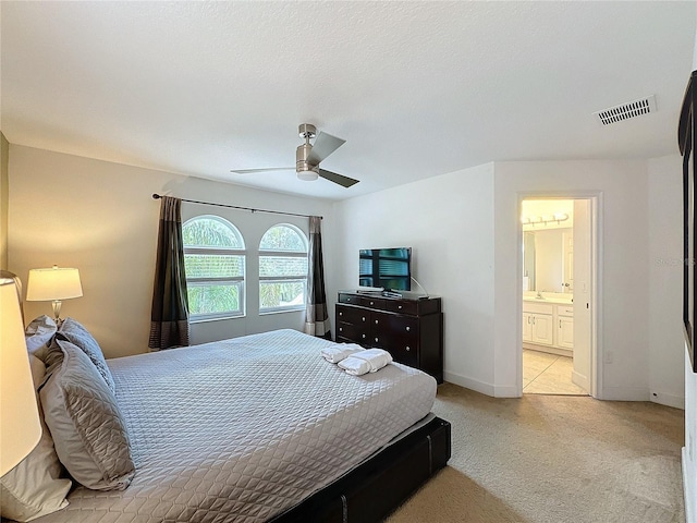 bedroom featuring ceiling fan, connected bathroom, and light colored carpet