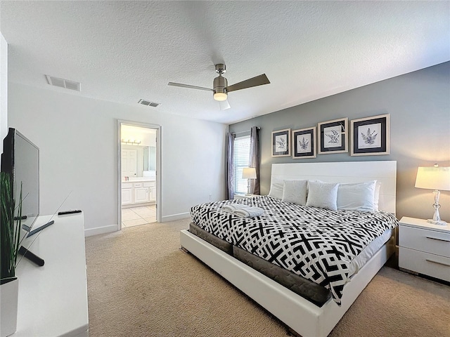 bedroom with a textured ceiling, light colored carpet, ceiling fan, and ensuite bath