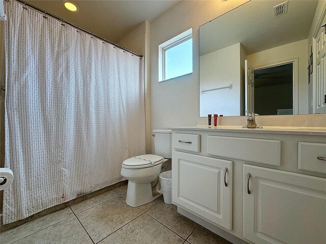 bathroom with toilet, vanity, and tile patterned flooring