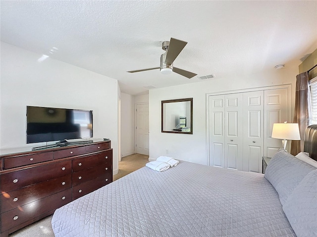 carpeted bedroom featuring a closet, ceiling fan, and a textured ceiling