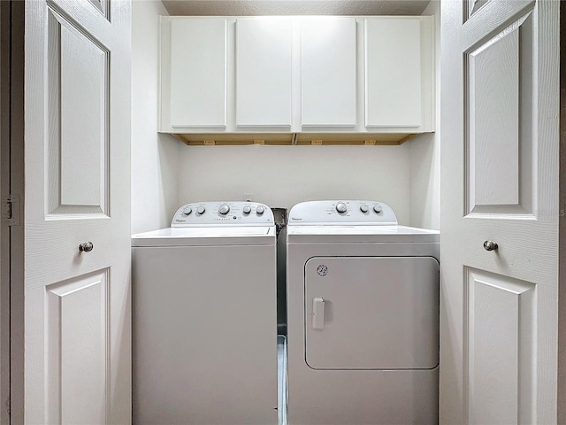 clothes washing area with washing machine and dryer and cabinets