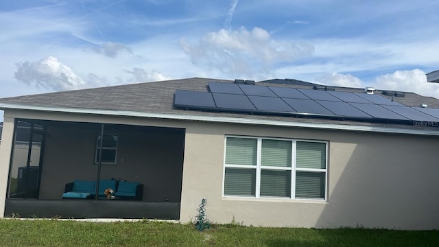 back of house featuring solar panels and a sunroom