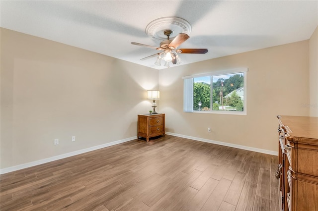 spare room featuring ceiling fan, baseboards, and wood finished floors