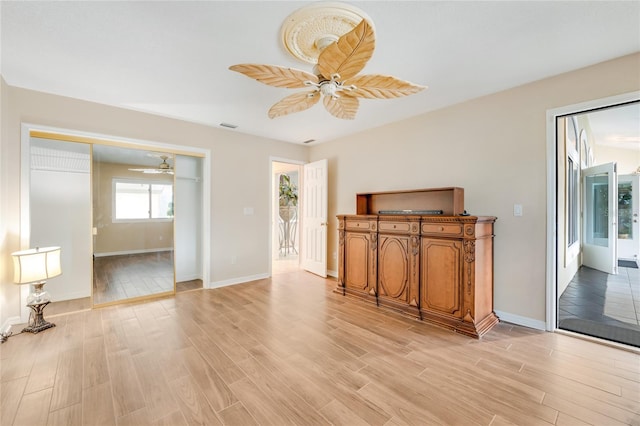 living room with visible vents, light wood-type flooring, a ceiling fan, and baseboards