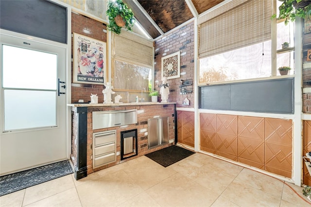 kitchen featuring brick wall, tile patterned flooring, and a sink