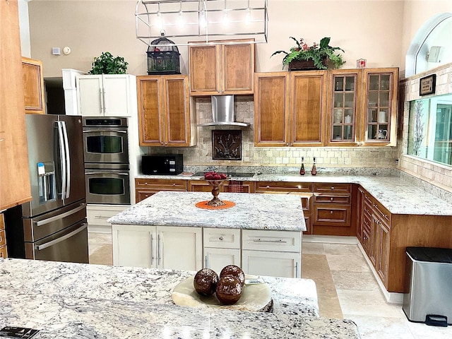 kitchen featuring black appliances, wall chimney exhaust hood, brown cabinets, and backsplash