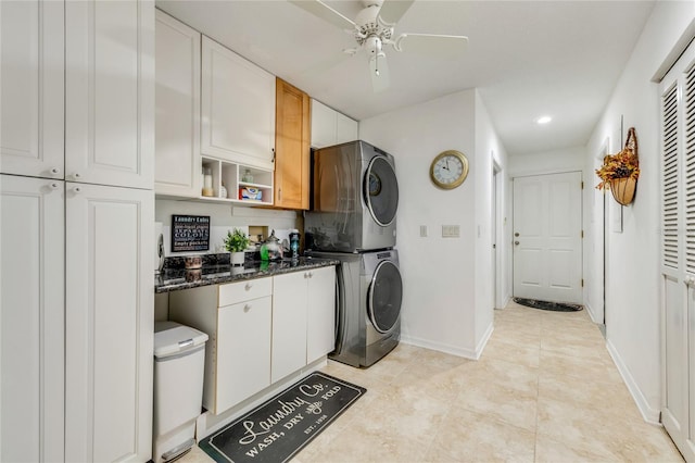 kitchen featuring stacked washing maching and dryer, baseboards, and white cabinets