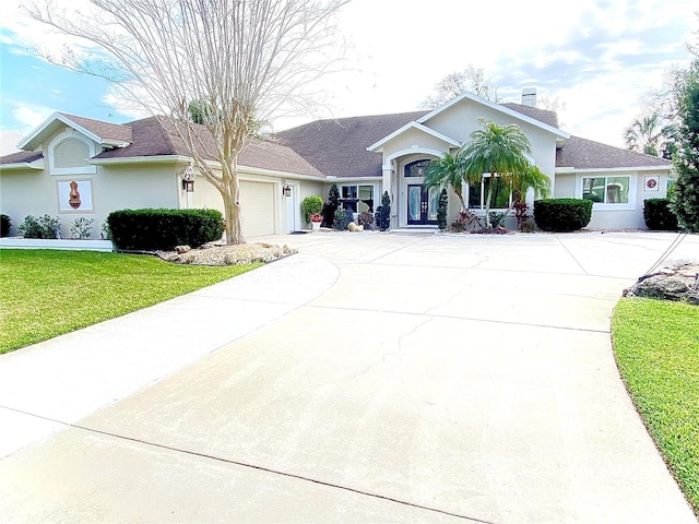 ranch-style house featuring driveway, a garage, a chimney, a front lawn, and stucco siding