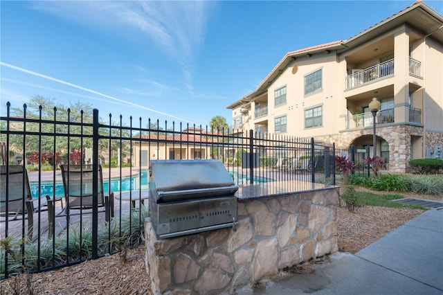 view of patio with a fenced in pool, area for grilling, and a balcony