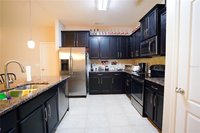 kitchen featuring sink, tasteful backsplash, stone countertops, pendant lighting, and appliances with stainless steel finishes