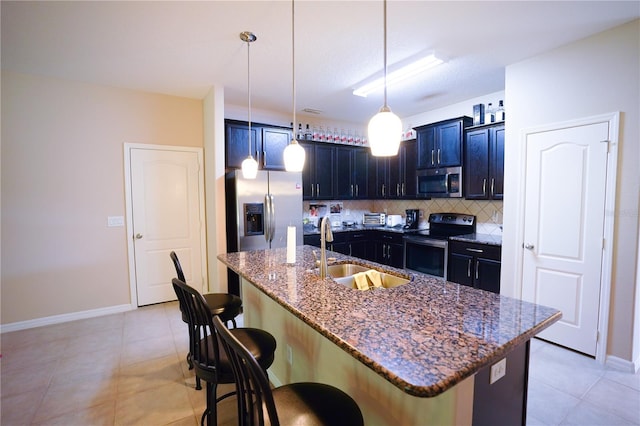 kitchen with appliances with stainless steel finishes, sink, a center island with sink, and a breakfast bar area