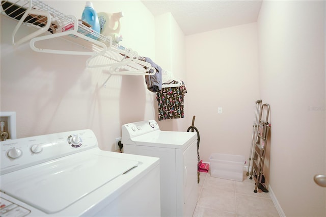 laundry area with washing machine and clothes dryer, a textured ceiling, and light tile patterned floors