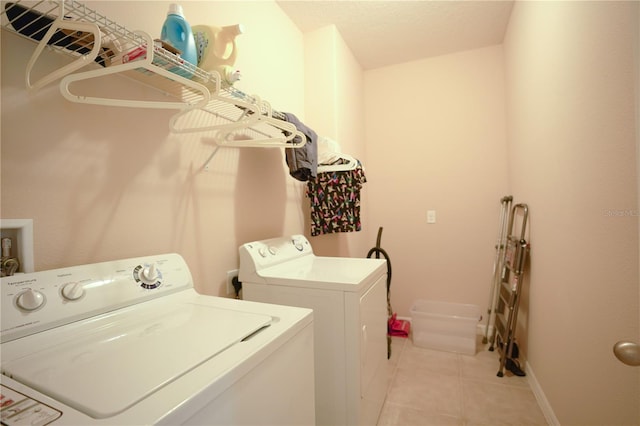 laundry area with independent washer and dryer and light tile patterned floors