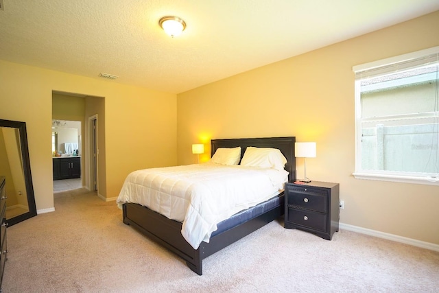 carpeted bedroom with connected bathroom and a textured ceiling