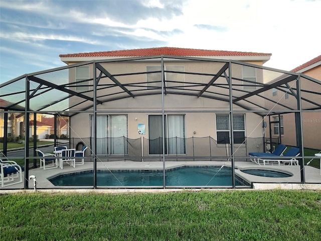 exterior space with glass enclosure, an in ground hot tub, a yard, and a patio area