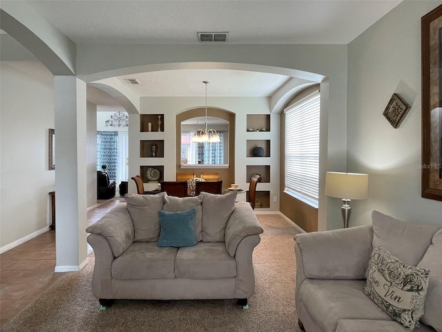 living room featuring a textured ceiling, built in shelves, carpet flooring, and a chandelier