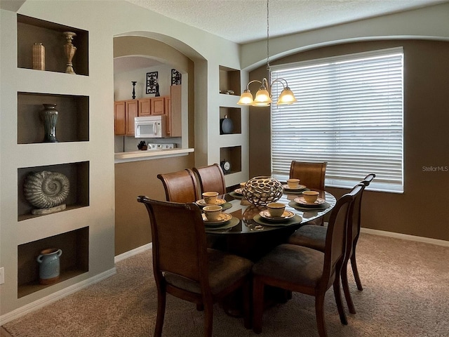 carpeted dining area with a textured ceiling, built in features, and a notable chandelier