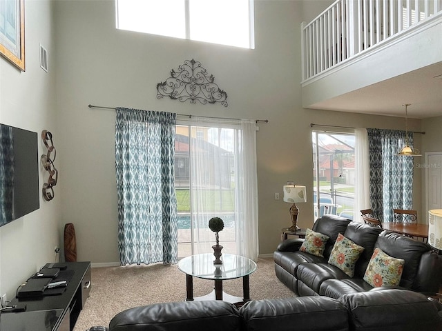 carpeted living room featuring plenty of natural light and a high ceiling