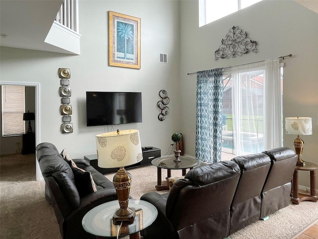 carpeted living room with plenty of natural light and a high ceiling