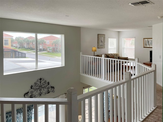 hall featuring a textured ceiling and carpet flooring