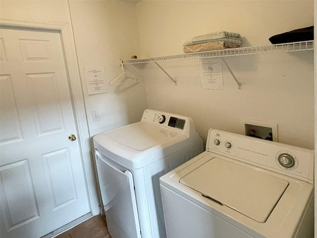 laundry room featuring washing machine and clothes dryer and dark tile patterned flooring