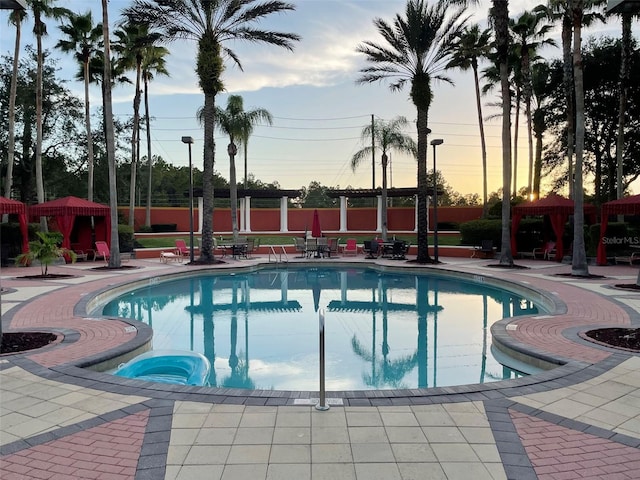 pool at dusk with a patio area