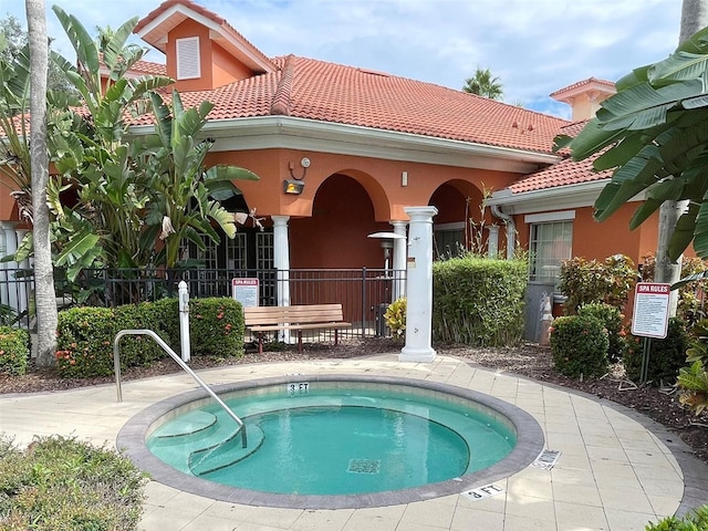 back of house with a community hot tub