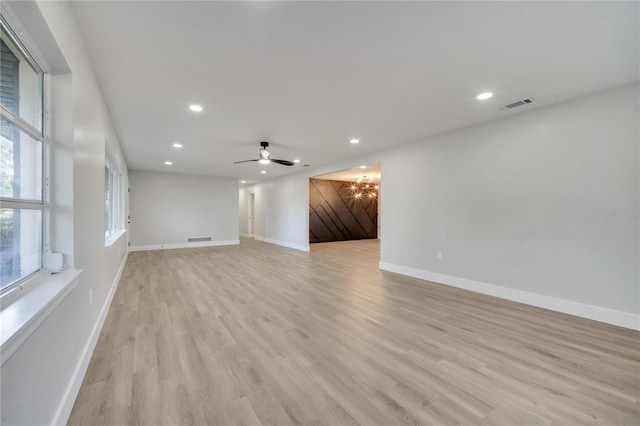 unfurnished living room featuring ceiling fan, light wood-type flooring, and a barn door