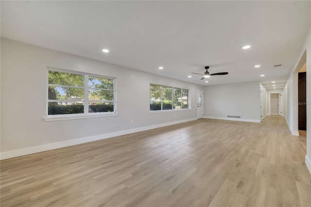 empty room with ceiling fan and light hardwood / wood-style flooring