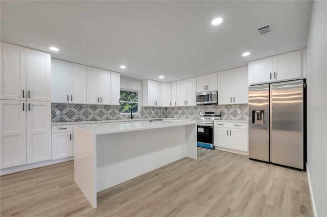 kitchen featuring stainless steel appliances, white cabinets, and light hardwood / wood-style floors