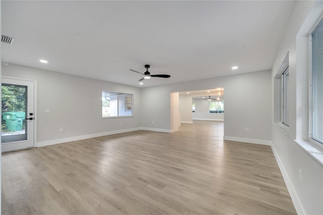 empty room with ceiling fan with notable chandelier and light wood-type flooring