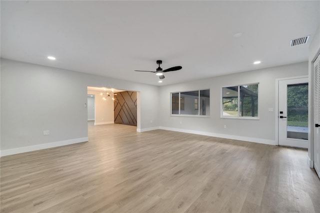 unfurnished living room with light wood-type flooring and ceiling fan with notable chandelier