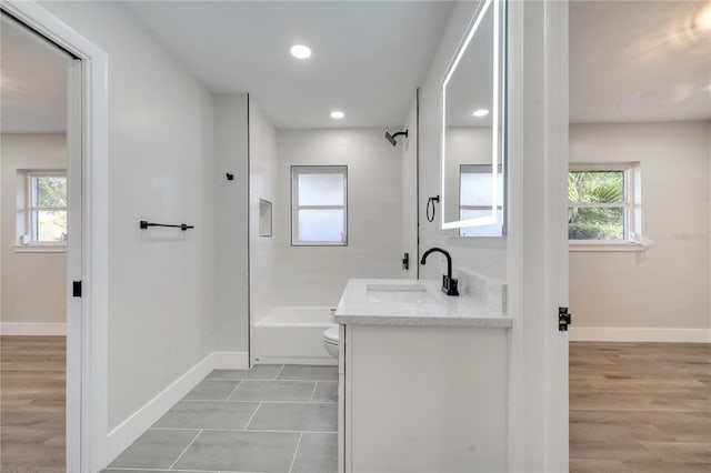 full bathroom featuring tiled shower / bath, vanity, hardwood / wood-style floors, and toilet