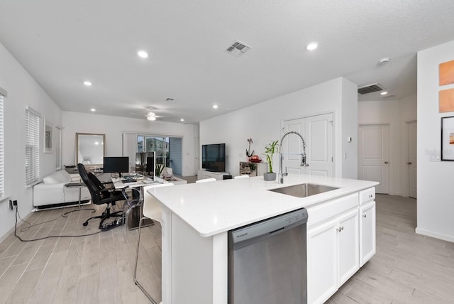 kitchen featuring light hardwood / wood-style floors, white cabinetry, an island with sink, stainless steel dishwasher, and sink