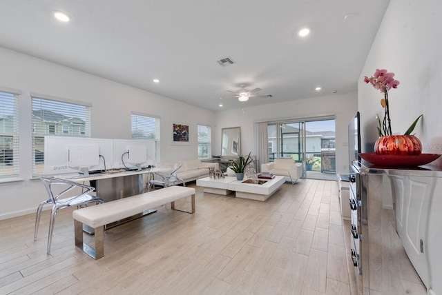 living room featuring ceiling fan, light hardwood / wood-style floors, and a wealth of natural light