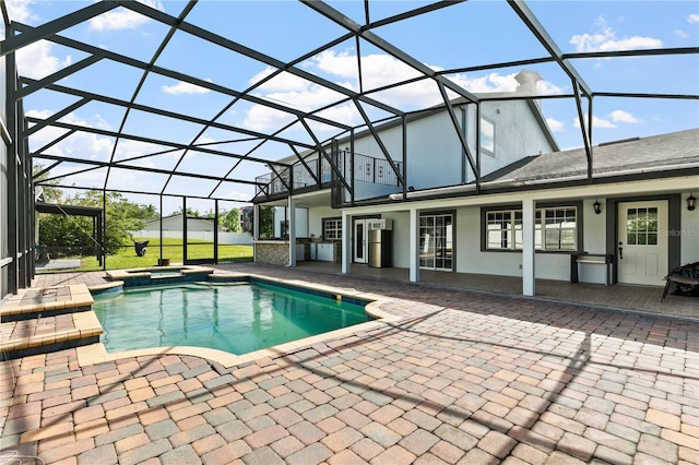 view of pool featuring an in ground hot tub, a patio, and glass enclosure