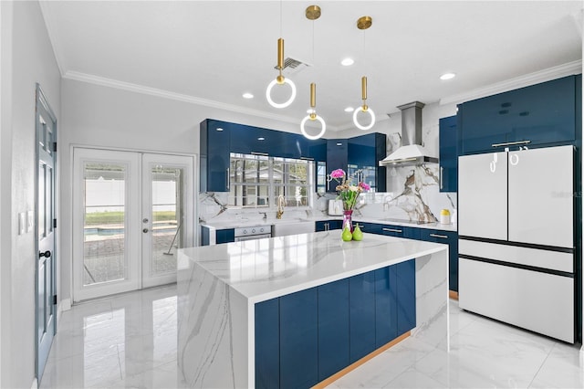 kitchen with wall chimney range hood, a kitchen island, blue cabinets, pendant lighting, and white refrigerator