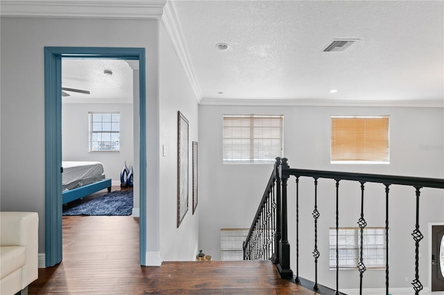 stairs featuring crown molding, a textured ceiling, and wood-type flooring