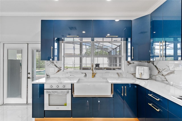 kitchen with blue cabinetry, sink, decorative backsplash, and white oven